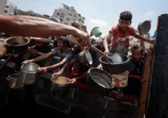 Palestinos se reúnem para receber alimentos de uma cozinha beneficente, em meio a uma crise de fome em Gaza