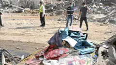 عمال الإنقاذ والمدنيون يسيرون بين أنقاض مبنى في منطقة الضاحية الجنوبية في بيروت، لبنان، بعد أن قصفته طائرات حربية إسرائيلية.