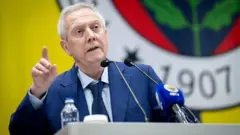 Aziz Yıldırım, arkada Fenerbahçe logolu bir kürsüde eli havada konuşma yapıyor.