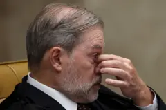 Toffoli sentado durante sessão do STF, fotografado de perfil, leva a mão esquerda ao nariz e aos olhos