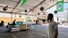 Kalani Mumbarak na garagem do Boi no Brasa durante preparativos para o jogo da Copa