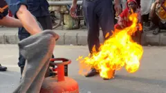 खाना पकाउने ग्यासमा आगो लाग्दा कसरी निभाउने भनेर नेपाल प्रहरीले सिकाउँदाको तस्बिर