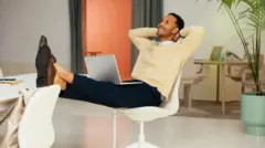 Un homme détendu et souriant à sa table de travail