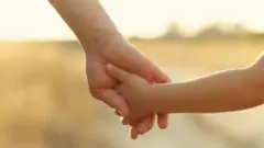 এক ব্যক্তি ও এক শিশুর হাত ধরার ক্লোজ-আপ শট