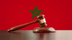 صورة لمطرقة كتلك التي يستخدمها القضاة وفي الخلفية علم المغرب