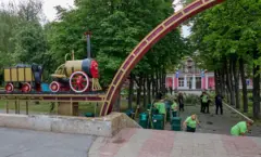 Люди в светоотражающих жилетах убирают обломки на аттракционе "Детская железная дорога" в Харькове