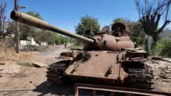 دبابة مدمرة في حي سكني بينما يستعيد الجيش السوداني السيطرة على بعض الأراضي ويعود بعض السكان النازحين إلى ولاية الخرطوم، السودان، 26 مارس/آذار 2025