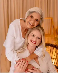 Mãe e filha abraçadas em retrato profissional usam roupas brancas