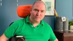 Andrew Gurza de camisa verde em cadeira de rodas