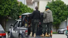 Awon olopaa meji naro mọ ọkọ wọn to n lọ, awọn kan jokoo sinu ọkọ naa.