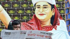 বাংলাদেশী পাঠক তৎকালীন বিরোধী নেতা শেখ হাসিনার পোস্টারের সামনে জরুরী অবস্থার খবর জানছেন, ১২-০১-২০০৭।