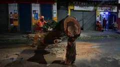 Um funcionário corta uma árvore caída em uma rua residencial após fortes rajadas de vento associadas à chegada de uma frente fria no Rio de Janeiro, Brasil, em 29 de julho de 2026.