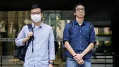 《立場新聞》前總編輯鍾沛權（右）、前署理總編輯林紹桐（左）在區域法院門前