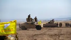 قطع حربية تحمل راية قوات سوريا الديمقراطية وعلى متنها جنود بقلب الصحراء