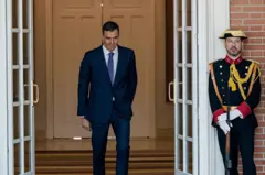 El presidente español, Pedro Sánchez, sale del Palacio de la Moncloa, por un acceso custodiado por un guardia con uniforme de gala.