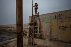 پسری روی دیوار جدیدی که برای محافظت از جاکارتا در برابر بالا رفتن سطح دریا ساخته‌ شده است، راه می‌رود