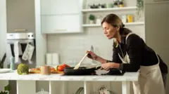 Kobieta w średnim wieku gotuje jedzenie w kuchni