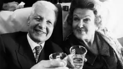 Чорно-біле фото Крогерів у літаку з напоями в руках