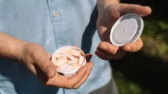 Чоловік показує камері невеликий контейнер з нікотиновими пакетиками