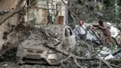 Dos personas caminan entre escombros tras un ataque con drones en Kyiv