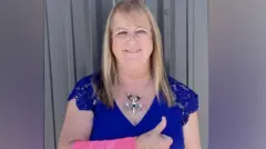 Peggy Jones muestra su brazo envuelto en vendas con el pulgar en alto. 