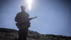 መሳሪያ ታጥቆ የቆመ ሰው