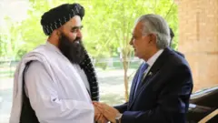  امیرخان متقی با اسحاق دار وزرای خارجه پاکستان و حکومت طالبان در یک دیدار رسمی دیده می‌شوند. آنها با یکدیگر دست داده‌اند و لبخند بر چهره دارند
