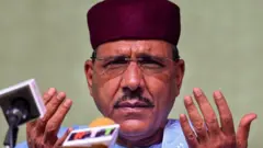 Mohamed Bazoum wari umaze gutorwa nka Perezida wa Niger, akora ikimenyetso n’ibiganza ku cyicaro gikuru cy’ishyaka rye, nyuma yuko atangajwe ko yatsinze amatora, aha ni i Niamey, muri Niger, ku itariki ya 23 Gashyantare (2) mu 2021