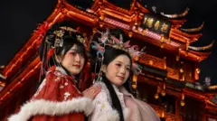 Women wearing traditional costumes pose for photographs in front of a Chinese temple