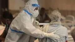 An Indian doctor wearing PPE examines a patient at a hospital in Delhi on 13 April 2021