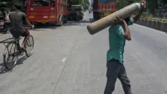 মুম্বাইয়ের রাস্তায় অক্সিজেন সিলিন্ডার বয়ে নিয়ে যাচ্ছেন একজন হাসপাতাল কর্মী