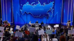 El presidente ruso Vladimir Putin (en el centro) participa en su rueda de prensa anual transmitida en directo con medios de comunicación rusos (federales y regionales) y extranjeros en la sala de conferencias Gostiny Dvor en Moscú, Rusia, el 19 de diciembre de 2025.