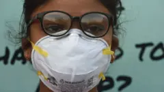 মুখে মাস্ক পরে বায়ু দূষণের প্রতিবাদ করছে এক ছাত্রী।