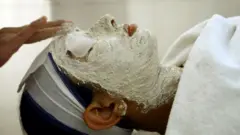 Una mujer india recibe un tratamiento facial en un salón de Nueva Delhi