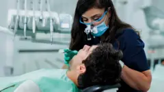 Dentista observa boca de paciente