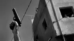 A hand holding a pistol in the air