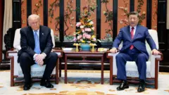 US President Donald Trump (L) and China's President Xi Jinping (R) sit on chairs in a room with ornamental Chinese decorations and furniture
