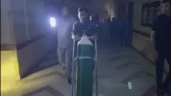 أحد أفراد طاقم التمريض في مستشفى الشفاء يحمل أسطوانة أكسجين