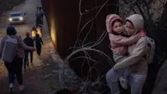 Mujer cruzando a la frontera con su hija en brazos