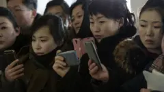 요리 대회를 지켜보며 카메라로 촬영하고 있는 평양 시민들