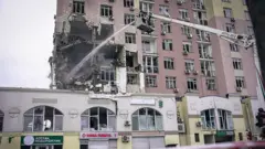 Rus füzelerinin isabet ettiği bir apartmanda ekiplerin vinç yardımıyla müdahale ettiği görülüyor.