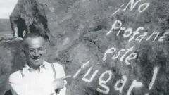 Gonzalo Rojas de joven en una imagen en blanco y negro, junto a una piedra que tiene una inscripción con pintura que pone "¡No profane este lugar!"