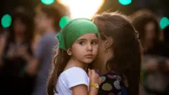 Una niña cargada por su madre.