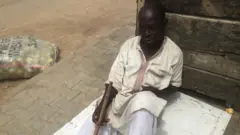 Mallam Adamu Makoda carri cane, sidon ontop ground
