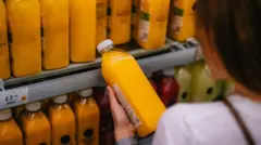 Mujer leyendo la etiqueta de un jugo de naranja en un supermercado.