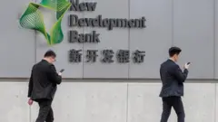 Pessoas passando em frente ao Banco de Desenvolvimento (NDB), conhecido como o 'Banco dos BRICS', durante a vista de Lula a Xangai, na China 