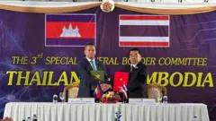 Kamboçya ve Tayland Savunma Bakanları bir masada el sıkışıyor.