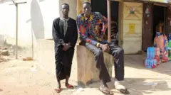 Awuche vit désormais avec son frère aîné (L) à Gambaga.