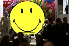 Emoji de rosto sorridente amarelo em exibição durante evento no ExCel, em Londres
