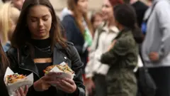 Жінки тримають у руках кебаб у булці